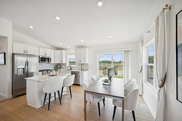 kitchen featuring backsplash, light countertops, lofted ceiling, appliances with stainless steel finishes, and a sink