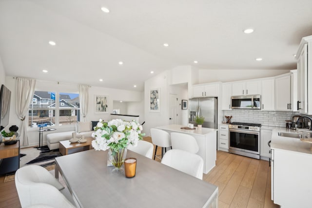 dining area with light wood finished floors, recessed lighting, and lofted ceiling