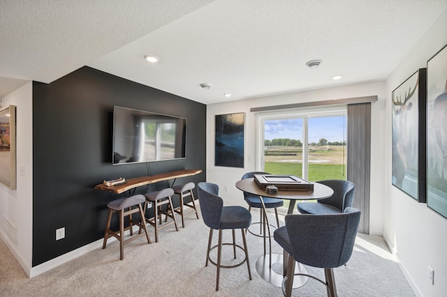 carpeted dining space with recessed lighting, baseboards, and a textured ceiling