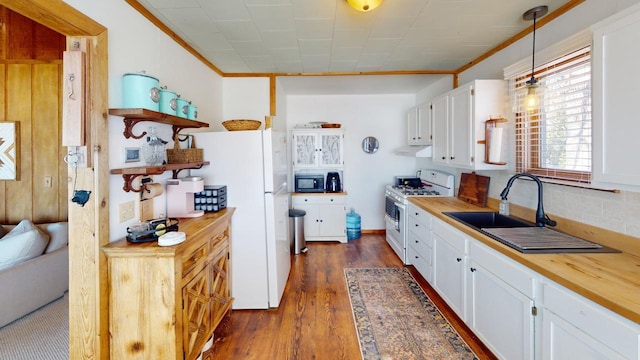 kitchen with white appliances, dark wood finished floors, open shelves, a sink, and butcher block counters