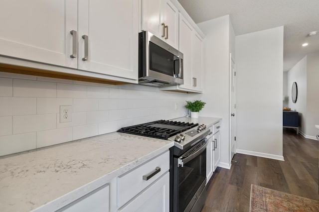 kitchen with light stone countertops, baseboards, stainless steel appliances, decorative backsplash, and dark wood-type flooring