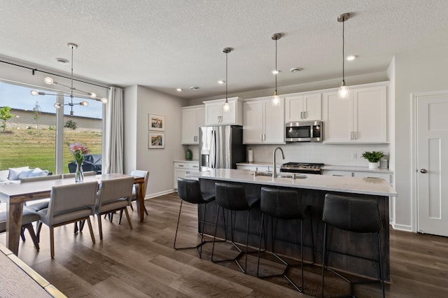 kitchen featuring dark wood-style floors, light countertops, appliances with stainless steel finishes, a kitchen bar, and tasteful backsplash