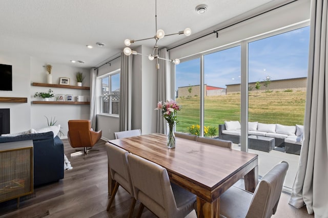 dining room featuring dark wood-style floors, visible vents, a textured ceiling, and baseboards