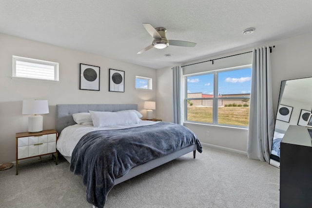 bedroom with a textured ceiling, carpet flooring, baseboards, and ceiling fan