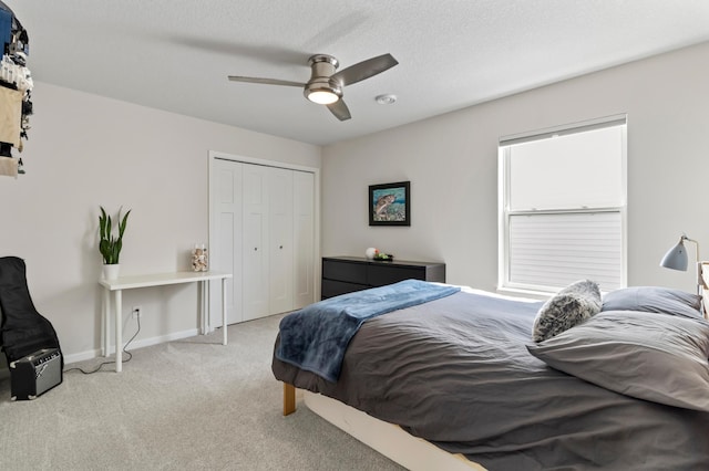 bedroom with a ceiling fan, a textured ceiling, a closet, carpet floors, and baseboards