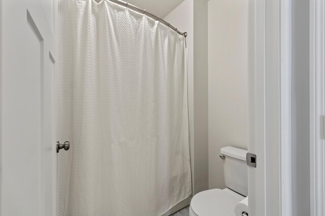 bathroom featuring a shower with curtain and toilet