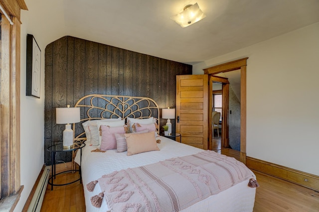 2538 Jefferson St NE, Minneapolis, MN 55418 - bedroom featuring wood finished floors, wooden walls, baseboards, and a baseboard heating unit