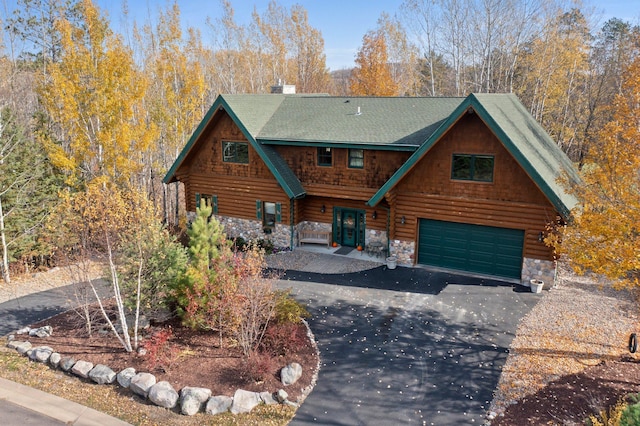 cabin featuring log siding, stone siding, and driveway