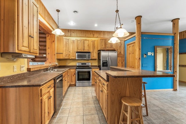 kitchen with a breakfast bar, a sink, a kitchen island, dark countertops, and stainless steel appliances