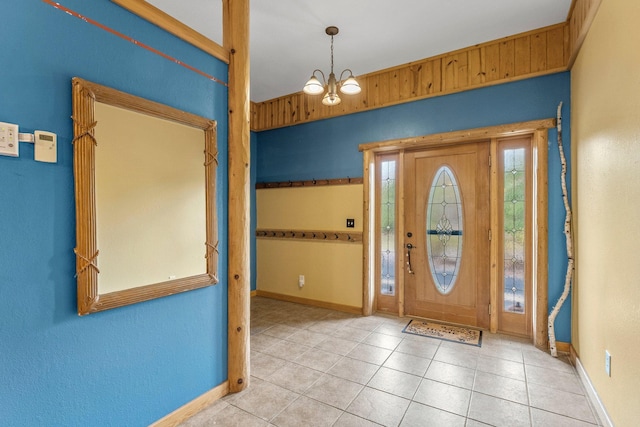 tiled foyer with baseboards and a chandelier