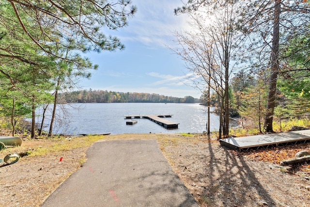 view of dock with a forest view and a water view