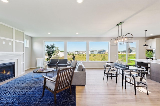 living area with recessed lighting, baseboards, a glass covered fireplace, and light wood finished floors