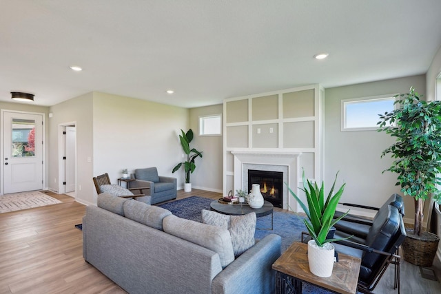 living area with recessed lighting, light wood-type flooring, a high end fireplace, and baseboards