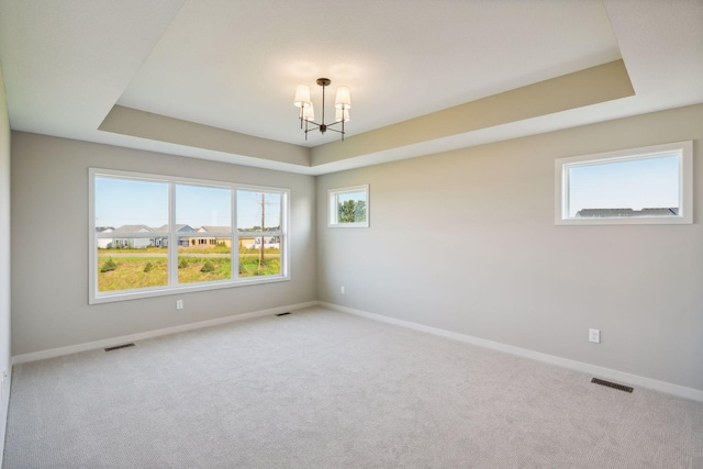 unfurnished room with a tray ceiling, baseboards, and a chandelier