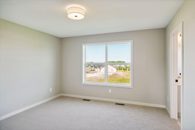 empty room featuring visible vents, light carpet, and baseboards