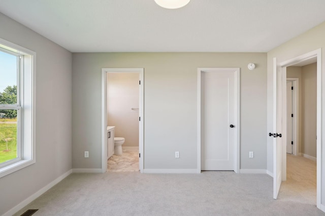 unfurnished bedroom featuring connected bathroom, baseboards, and light colored carpet