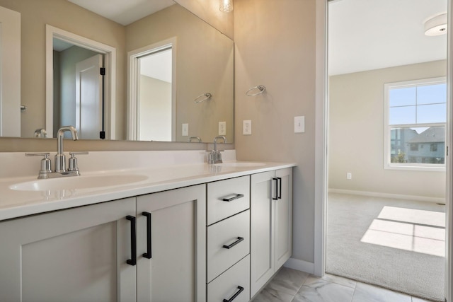 bathroom featuring a sink, baseboards, marble finish floor, and double vanity