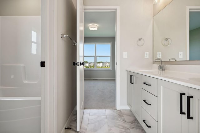 bathroom with baseboards, double vanity, a bathtub, marble finish floor, and a sink