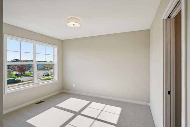 carpeted spare room featuring visible vents and baseboards