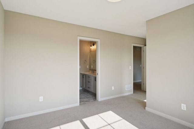 unfurnished bedroom featuring visible vents, light carpet, baseboards, and ensuite bathroom