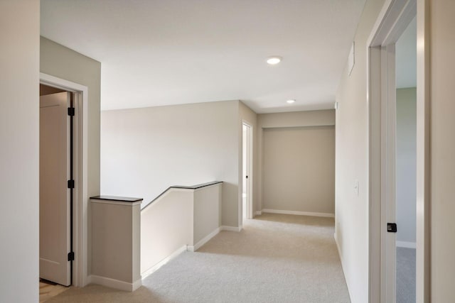 hall featuring an upstairs landing, light carpet, and baseboards