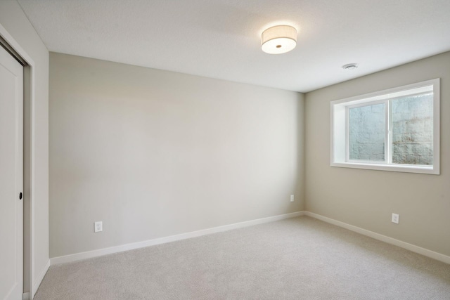 empty room featuring baseboards and light carpet