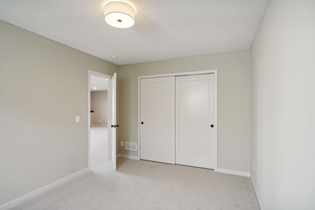 unfurnished bedroom with light colored carpet, visible vents, a closet, and baseboards