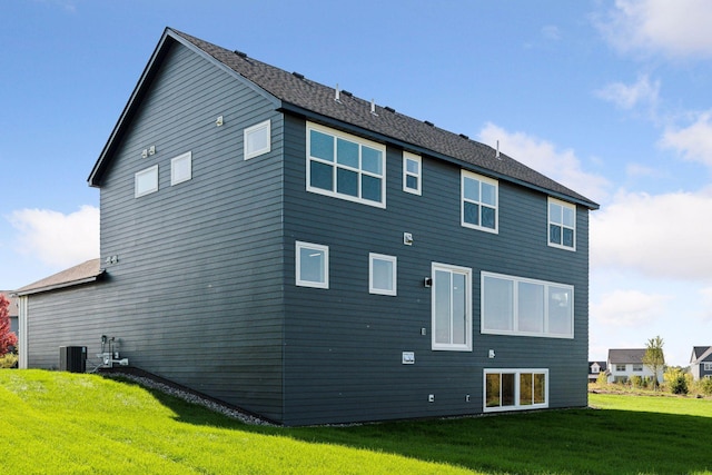 rear view of house featuring a lawn and central AC