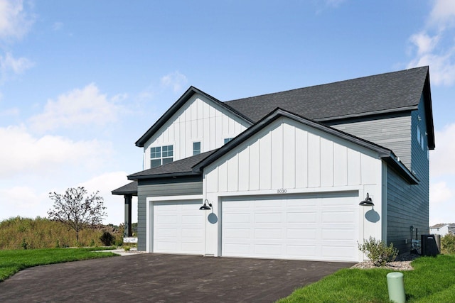 view of front of property featuring board and batten siding, a shingled roof, aphalt driveway, central air condition unit, and an attached garage