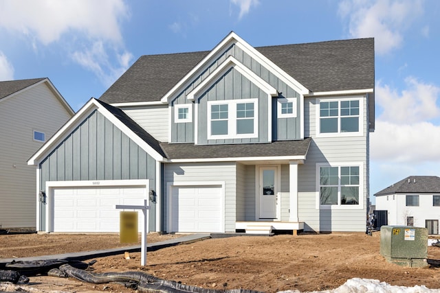 view of front of house featuring central AC unit, board and batten siding, an attached garage, and roof with shingles