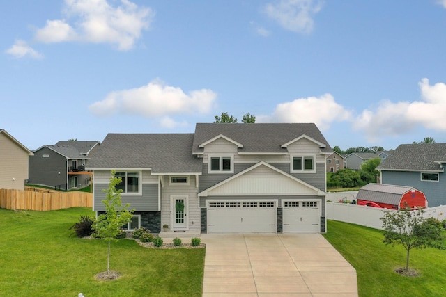 view of front of home with driveway, a front lawn, stone siding, fence, and an attached garage