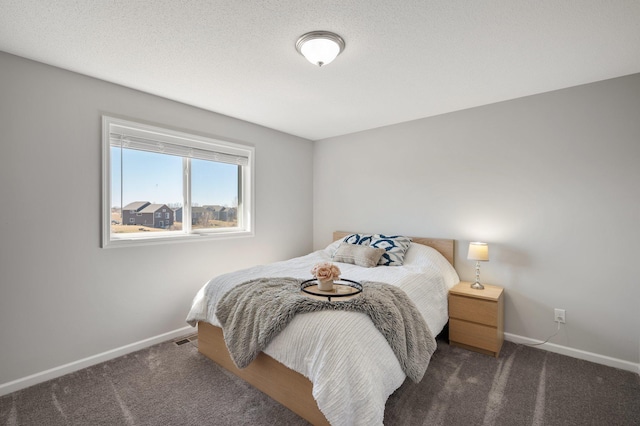 carpeted bedroom featuring a textured ceiling and baseboards