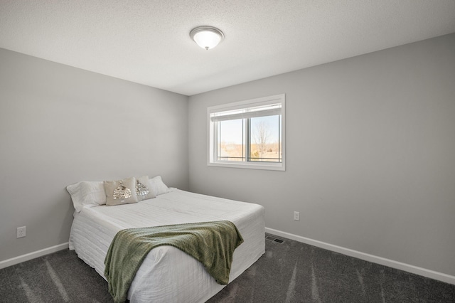 bedroom featuring baseboards, dark carpet, and a textured ceiling