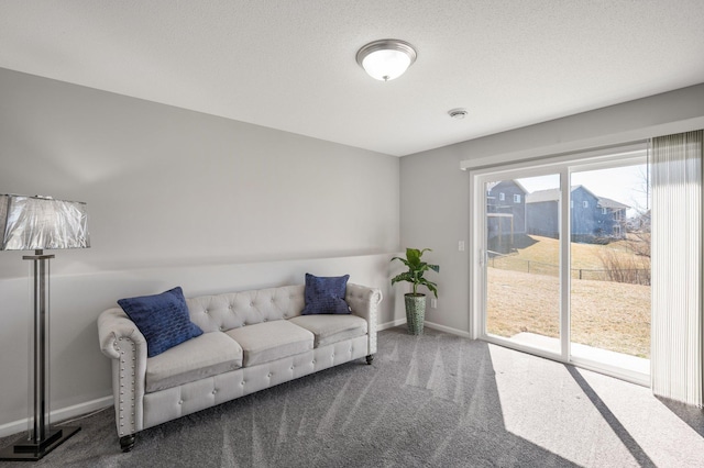 carpeted living room featuring baseboards and a textured ceiling