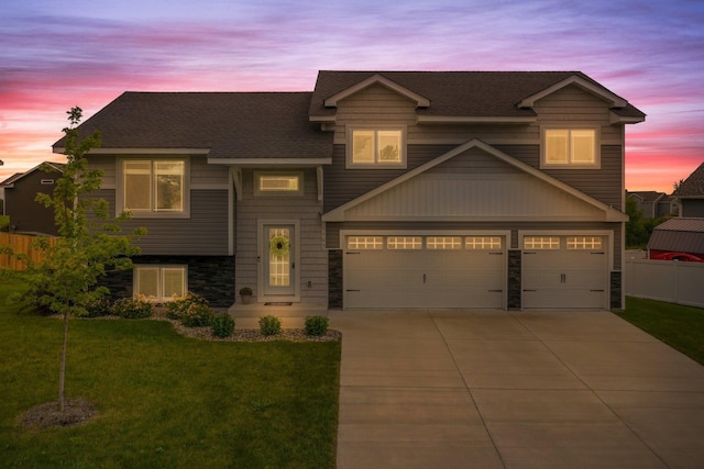 view of front of house with driveway, fence, a yard, roof with shingles, and an attached garage