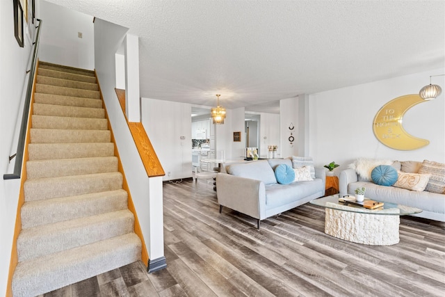 living area featuring wood finished floors, stairway, a textured ceiling, and baseboards