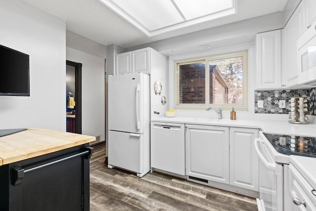 kitchen with white appliances, a sink, wooden counters, and white cabinets