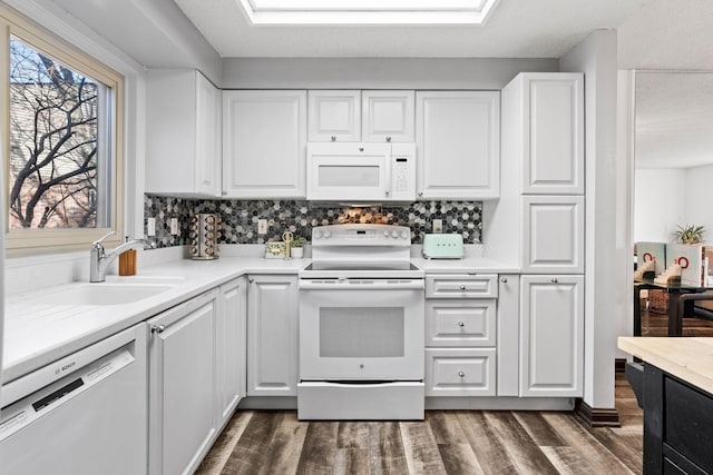 kitchen with white appliances, a sink, dark wood finished floors, and white cabinetry