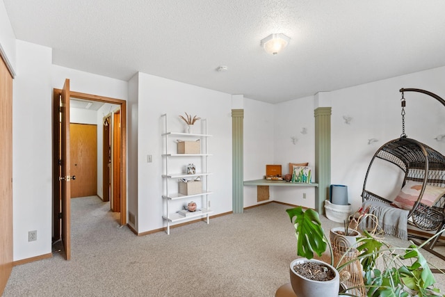 bedroom featuring light carpet, a textured ceiling, baseboards, and a desk