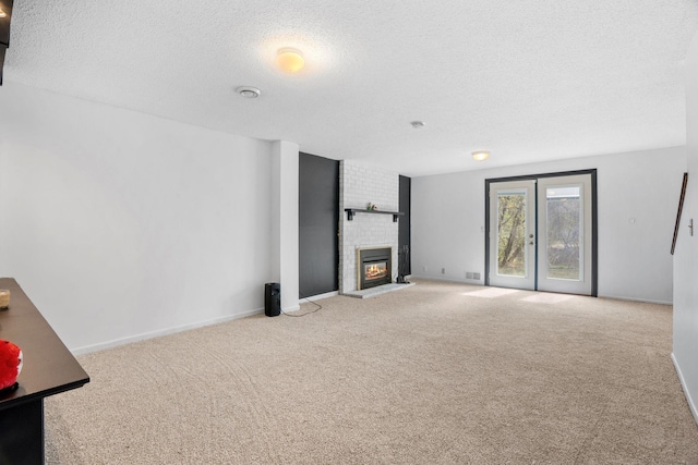 unfurnished living room with a textured ceiling, carpet flooring, a fireplace, and baseboards