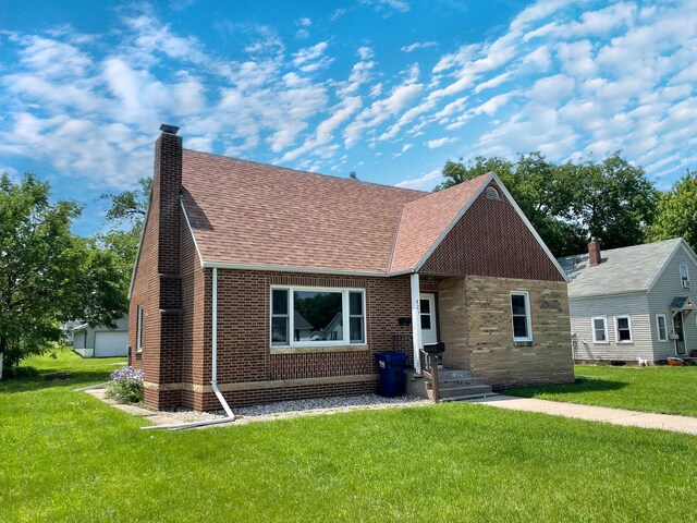 421 Van Dusen St, Springfield, MN 56087 - view of front of home featuring roof with shingles, a front yard, a chimney, and brick siding