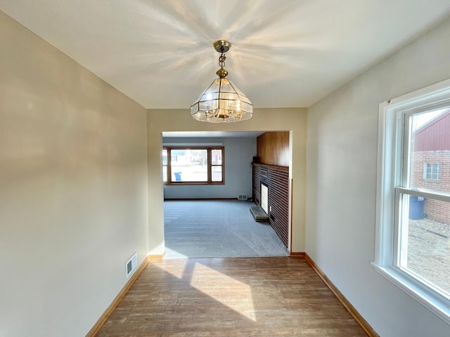 421 Van Dusen St, Springfield, MN 56087 - unfurnished living room with a chandelier, baseboards, wood finished floors, and a fireplace