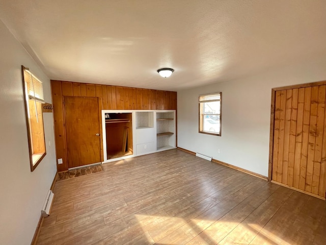 421 Van Dusen St, Springfield, MN 56087 - unfurnished bedroom with wood finished floors, baseboards, a closet, wood walls, and baseboard heating