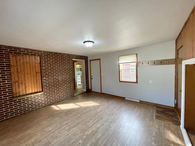 421 Van Dusen St, Springfield, MN 56087 - unfurnished living room featuring wood finished floors, brick wall, a baseboard heating unit, and baseboards