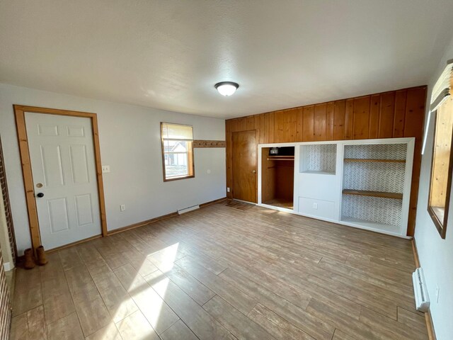 421 Van Dusen St, Springfield, MN 56087 - unfurnished bedroom with wood finished floors, baseboard heating, a closet, wooden walls, and baseboards