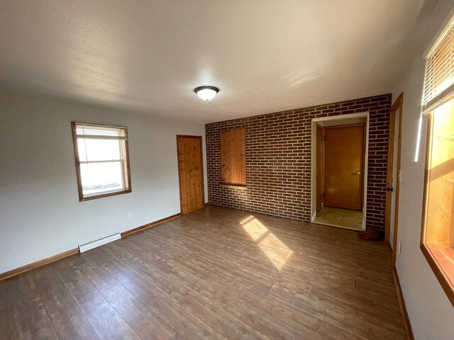 421 Van Dusen St, Springfield, MN 56087 - spare room with wood finished floors, baseboards, brick wall, and a baseboard heating unit