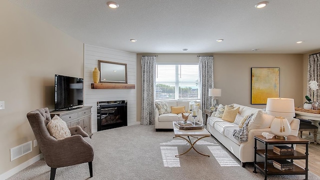 living area with baseboards, visible vents, recessed lighting, a textured ceiling, and a large fireplace