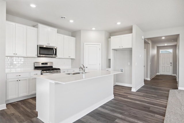 kitchen featuring a center island with sink, a sink, dark wood-style floors, white cabinetry, and appliances with stainless steel finishes