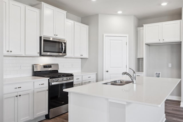 kitchen with a sink, stainless steel appliances, dark wood-style floors, and a center island with sink