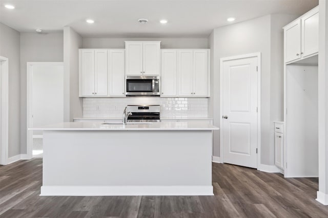 kitchen featuring decorative backsplash, a center island with sink, appliances with stainless steel finishes, and dark wood-style flooring